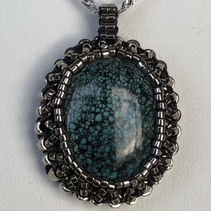 Tibetan Turquoise cabochon pendant framed by a cameo of glass micro-beading in metallic silver tone