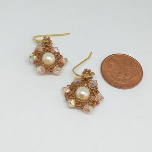 Fine beaded snowflake earrings with freshwater pearl centerpiece circled by a mandala of metallic micro-beading and Swarovski crystal