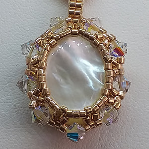 Mother of pearl cabochon pendant framed by fine beading of metallic champagne micro-beads and Swarovski crystal