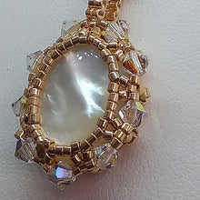 Load image into Gallery viewer, Mother of pearl cabochon pendant framed by fine beading of metallic champagne micro-beads and Swarovski crystal