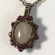 Load image into Gallery viewer, Opaque pink moonstone cabochon pendant framed by fine beading of metallic bronze micro-beads and facetted garnet