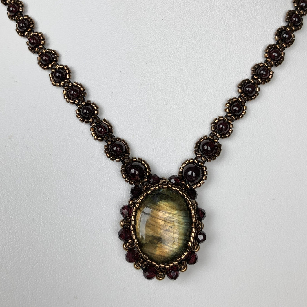 Golden flash Labradorite cabochon pendant necklace framed by fine beading of metallic bronze micro-beads and facetted garnet on garnet fine beaded chain