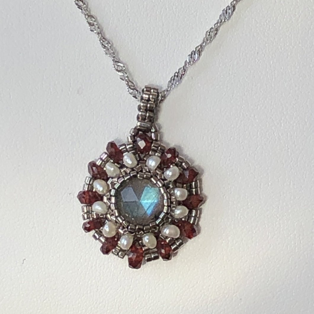 Fine beaded mandala style charm pendant with labradorite centerpiece surrounded by freshwater pearl and garnet gemstone