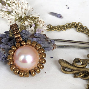 Pearl pendant necklace. Beaded jewellery. Large round freshwater pearl surrounded by metallic bronze-tone glass beads.