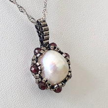 Load image into Gallery viewer, Large baroque freshwater pearl surrounded by metallic micro-beading with facetted garnet, suspended on trace chain.