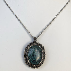 Tibetan Turquoise cabochon pendant framed by a cameo of glass micro-beading in metallic silver tone on a diamond cut steel twisted French chain